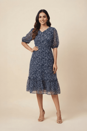 Woman wearing a navy blue floral ruffle midi dress with a V-neckline and sheer puff sleeves