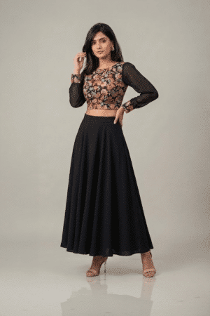 Woman wearing a black floral embroidered dress with sheer sleeves and a flowing flared skirt