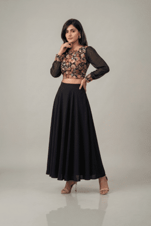 Woman wearing a black floral embroidered dress with sheer sleeves and a flowing flared skirt
