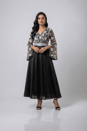Woman wearing a black gown with a monochrome printed wrap bodice, flared kimono sleeves and a flowing maxi skirt