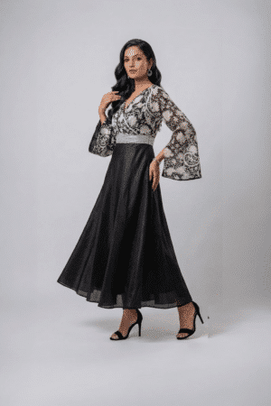 Woman wearing a black gown with a monochrome printed wrap bodice, flared kimono sleeves and a flowing maxi skirt