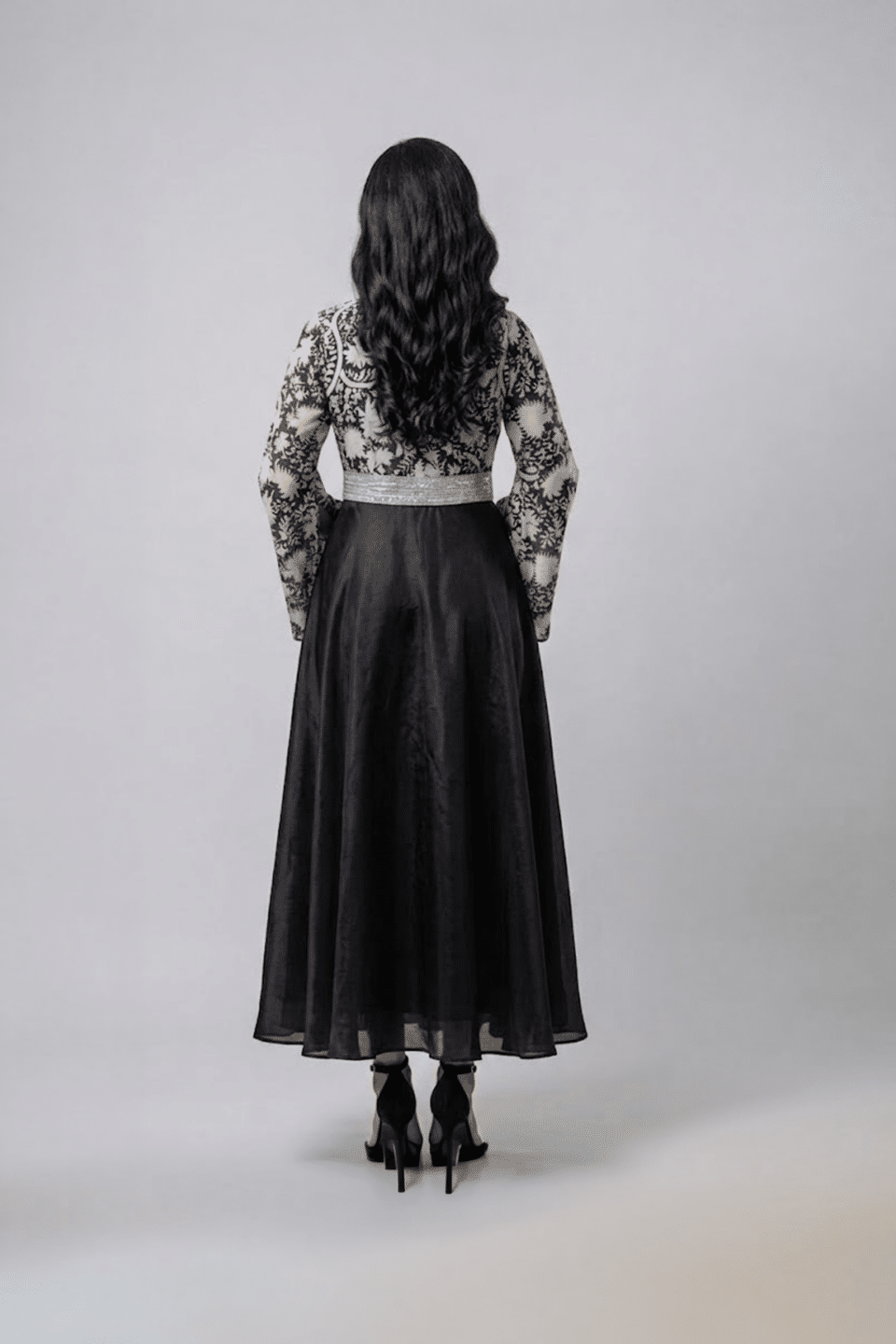 Woman wearing a black gown with a monochrome printed wrap bodice, flared kimono sleeves and a flowing maxi skirt