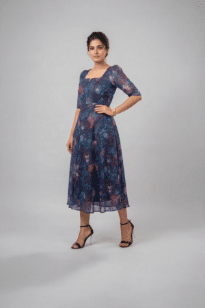 Woman wearing a navy blue floral midi dress with a square neckline, puff sleeves and an A-line silhouette