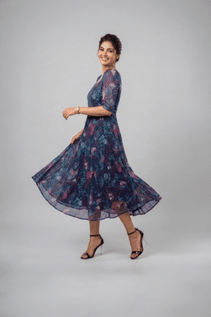 Woman wearing a navy blue floral midi dress with a square neckline, puff sleeves and an A-line silhouette