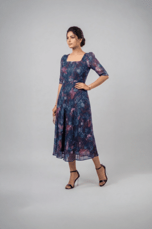 Woman wearing a navy blue floral midi dress with a square neckline, puff sleeves and an A-line silhouette