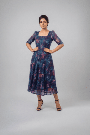 Woman wearing a navy blue floral midi dress with a square neckline, puff sleeves and an A-line silhouette