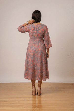 Woman wearing a grey floral print midi dress with a V-neckline, three-quarter bell sleeves and a flared silhouette