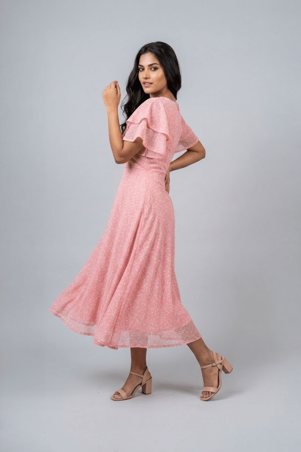 Woman wearing a soft pink midi dress with layered flutter sleeves and a flowing A-line silhouette