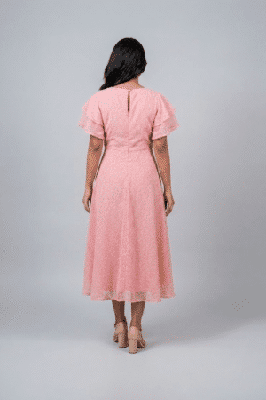 Woman wearing a soft pink midi dress with layered flutter sleeves and a flowing A-line silhouette
