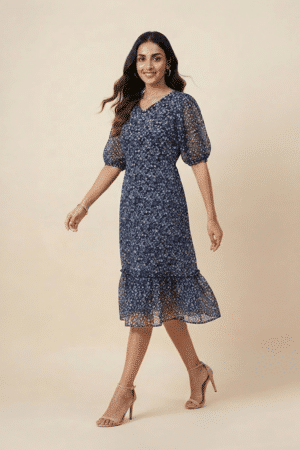 Woman wearing a navy blue floral ruffle midi dress with a V-neckline and sheer puff sleeves