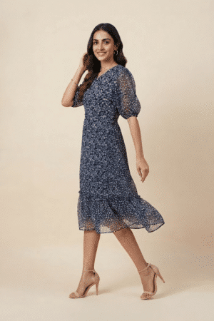 Woman wearing a navy blue floral ruffle midi dress with a V-neckline and sheer puff sleeves