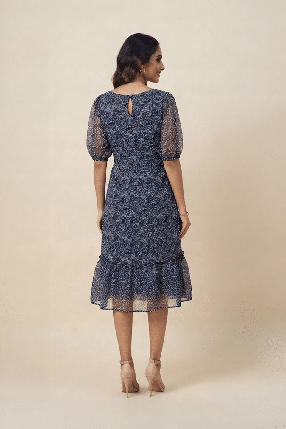 Woman wearing a navy blue floral ruffle midi dress with a V-neckline and sheer puff sleeves