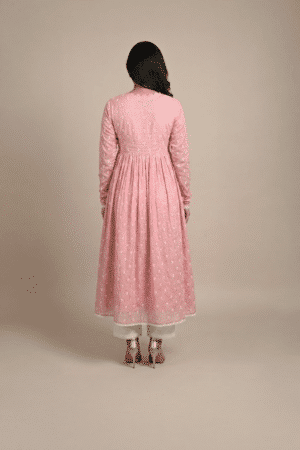 Woman wearing a dusty pink embroidered Anarkali with a scalloped V-neckline, long sleeves and white pants