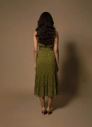 Model wearing an olive green halter neck midi dress with polka dots and a satin waist tie from Ivory by Radhika.