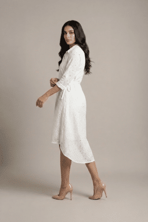 woman wearing a white cotton eyelet shirt dress with three quarter sleeves and waist tie
